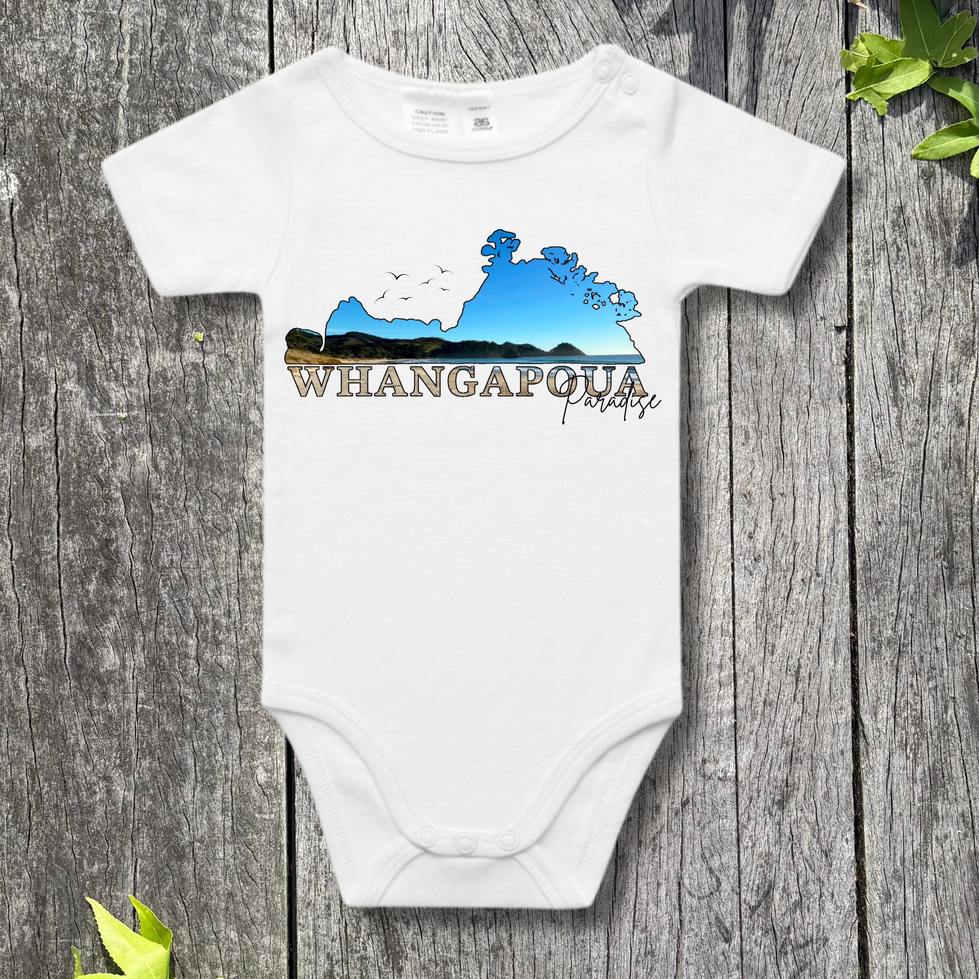 White baby onesie with a graphic design on a wooden surface
